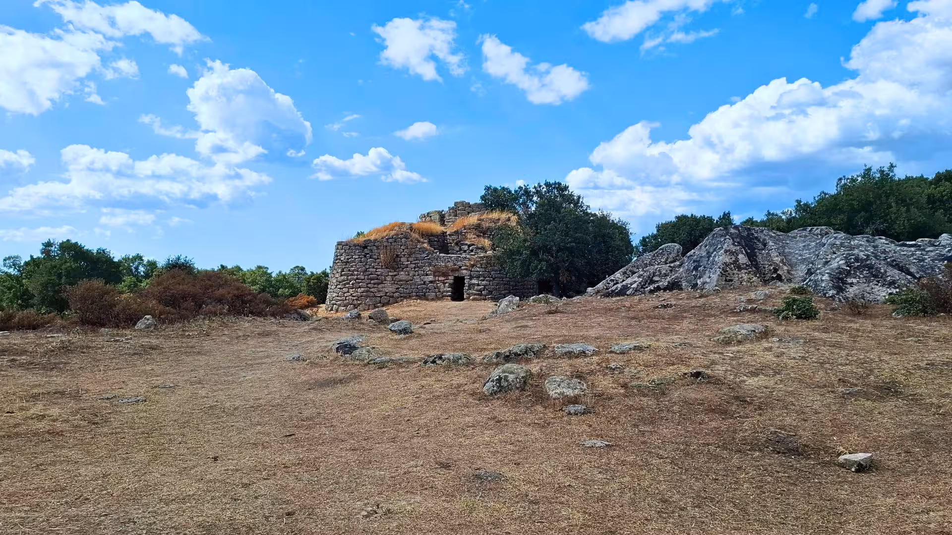 Explore the ancient stone ruins of the Loelle archaeological site in Buddusò under a bright blue sky.