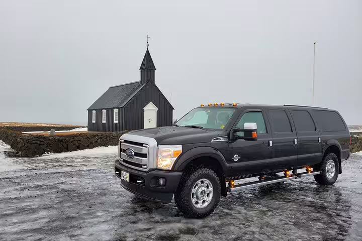 Private 4x4 tour vehicle parked near historic black Budir Church on Snaefellsnes Peninsula day trip Iceland