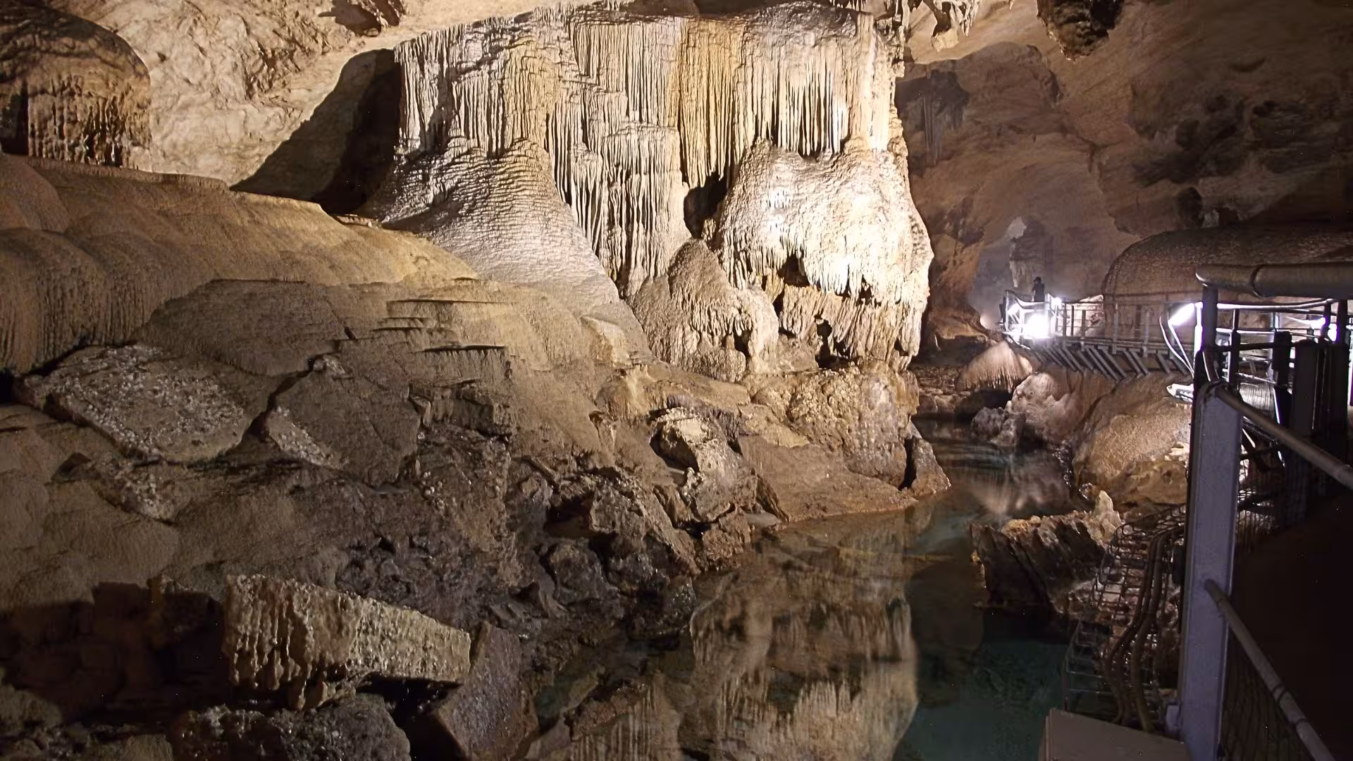 Inside Bue Marino Caves featuring impressive stalactites and a serene, illuminated walkway along the cave walls.