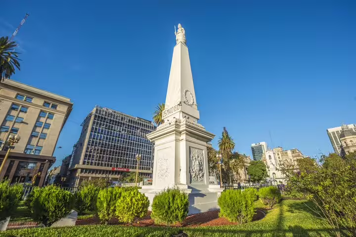 Pyramid of May monument in Plaza de Mayo, Buenos Aires, surrounded by green gardens and city buildings