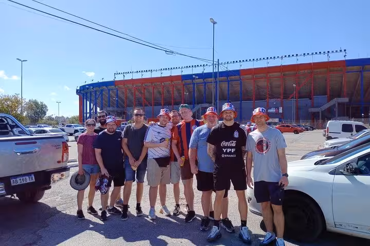 Travel group outside a Buenos Aires stadium before a local matchday experience, wearing team colors and hats