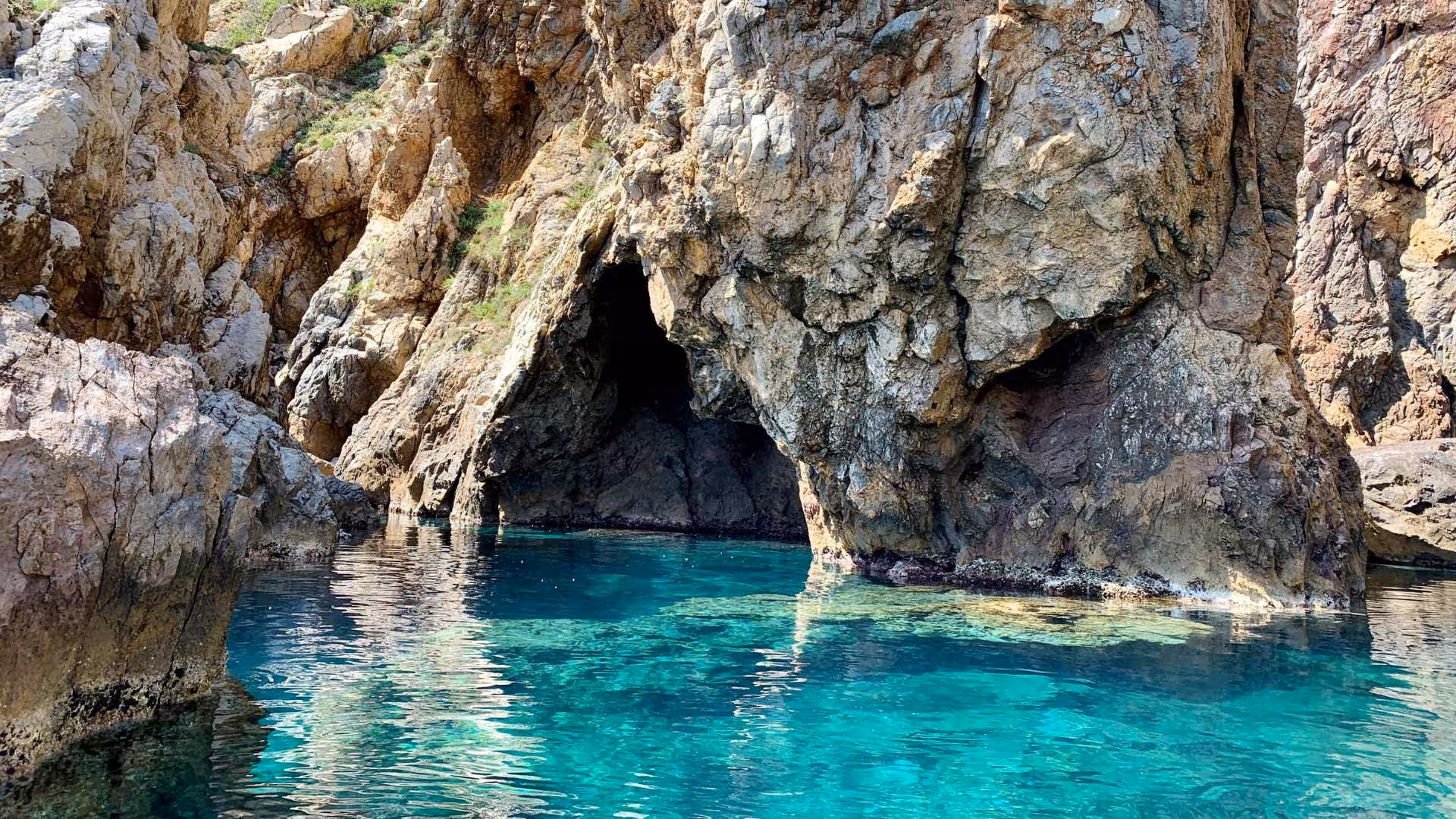 Stunning view of rugged rock formations and clear blue waters near Pan di Zucchero, ideal for scenic dinghy tours.
