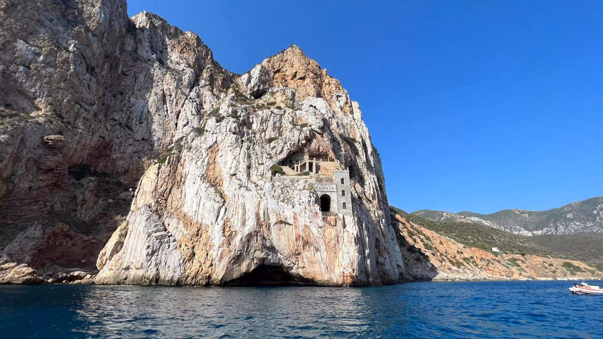 Explore Porto Flavia's dramatic cliffside architecture on our Buggerru dinghy tour, a Sardinian coastal marvel.