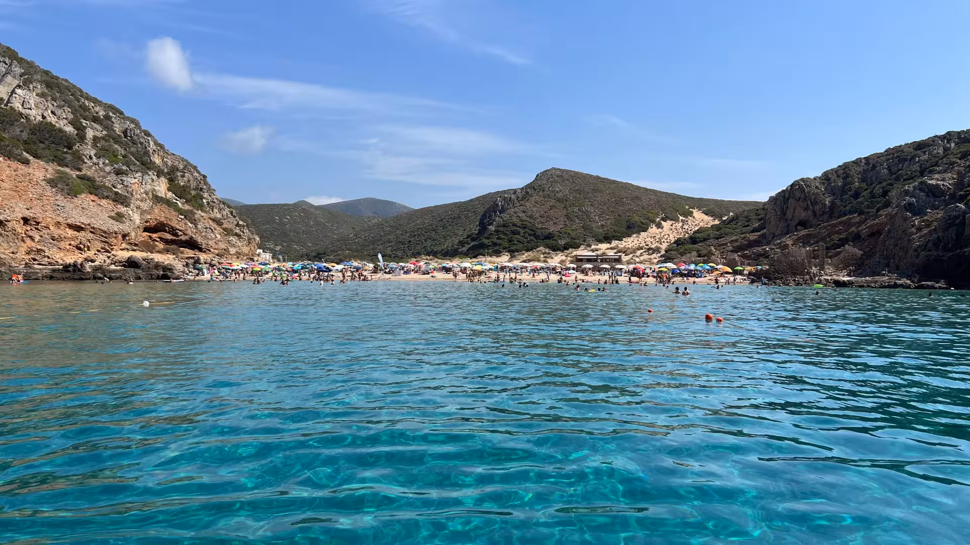 Enjoy clear turquoise waters and vibrant beach scene on a Buggerru dinghy tour to Porto Flavia.