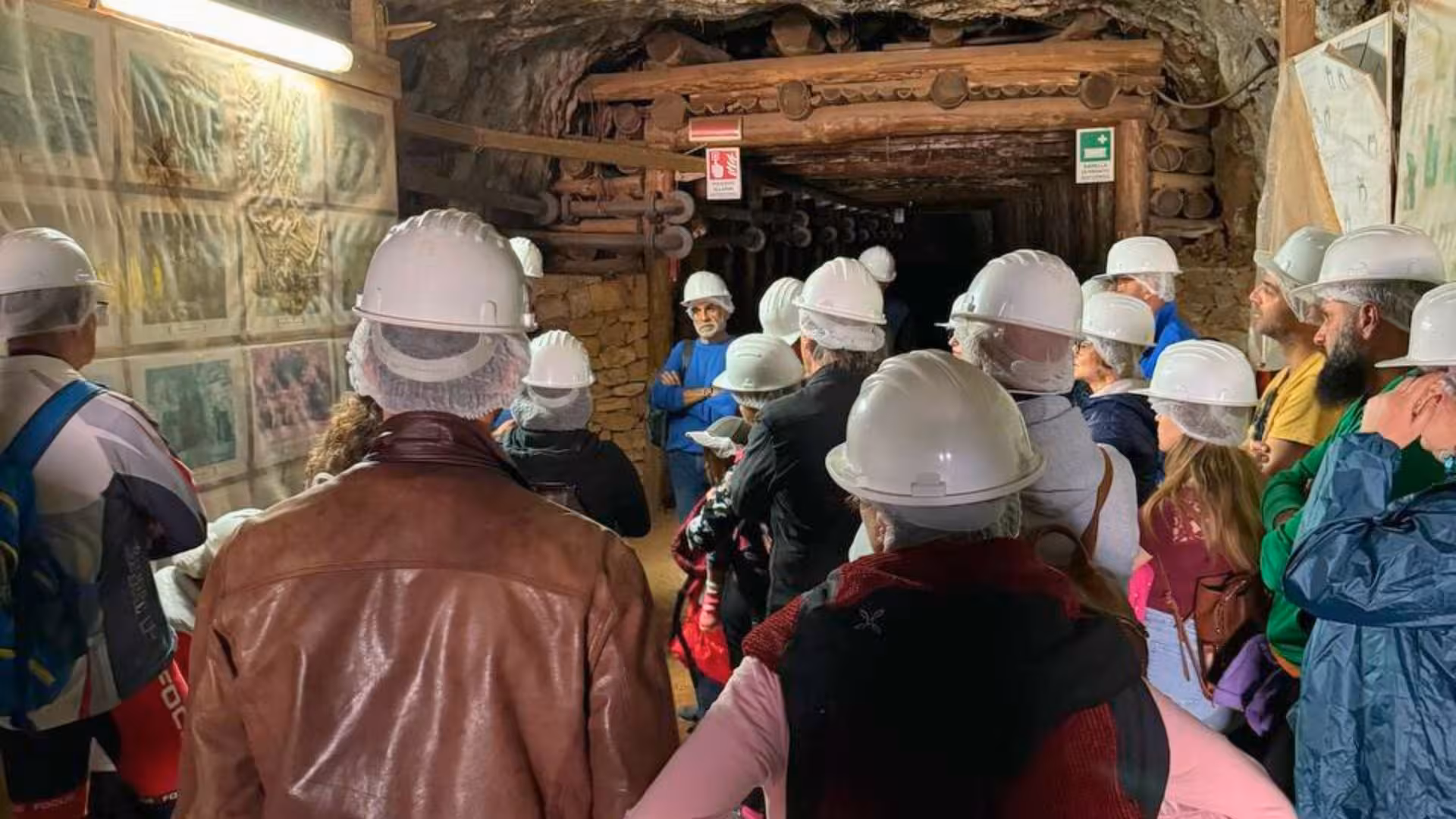 Tour group wearing helmets explores the historic Galleria Henry tunnel in Buggerru, learning about Sardinia’s mining heritage.