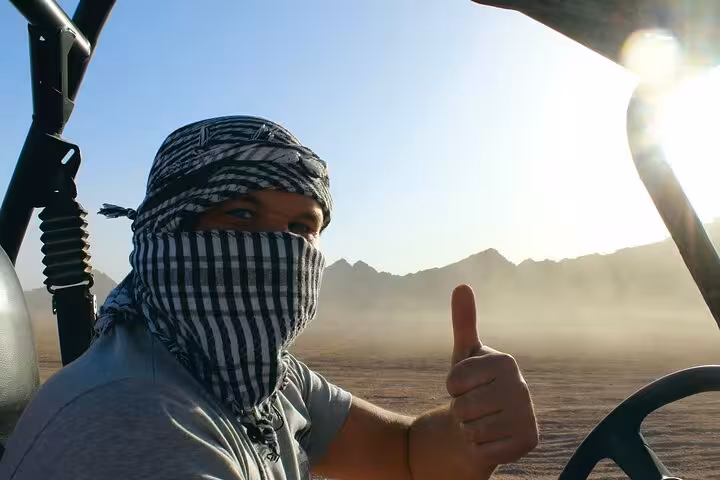 Buggy safari driver in keffiyeh giving thumbs up in Hurghada desert, off-road sea and mountain adventure