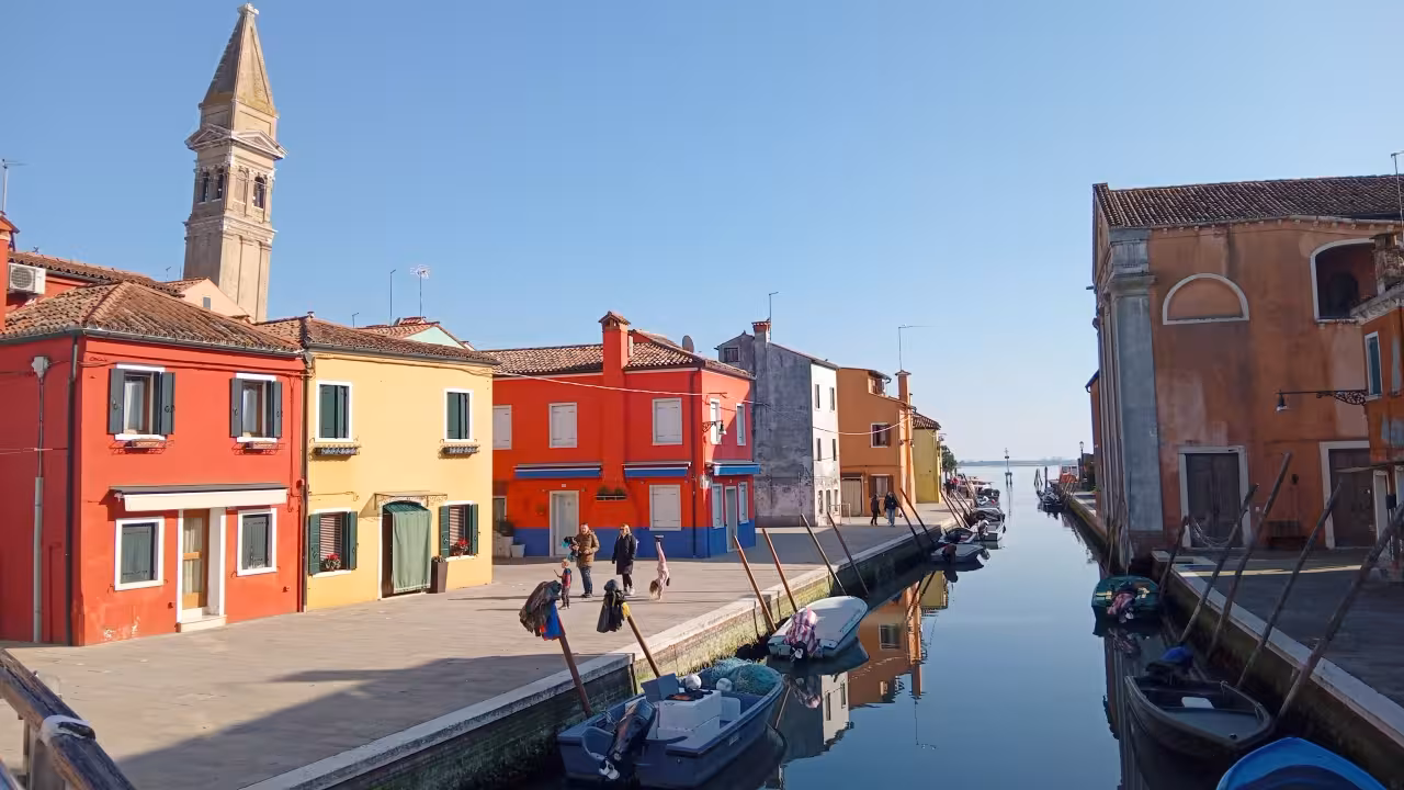 Burano canal promenade with colorful houses and boats, classic stop for lace and history tour to Mazzorbo