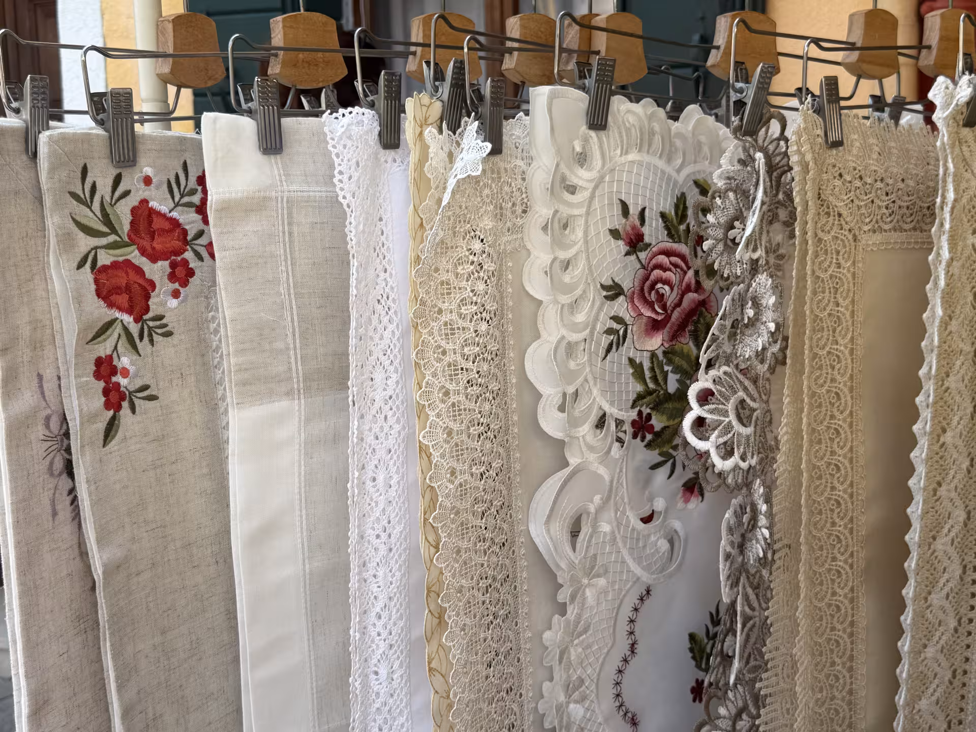 Elegant handmade lace and embroidered fabrics on display in Burano, showcasing traditional Venetian craftsmanship.