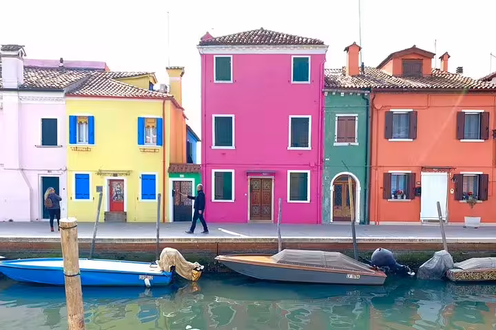 Brightly painted Burano houses with boats moored along the canal, ideal for a picturesque Grand Canal boat tour.