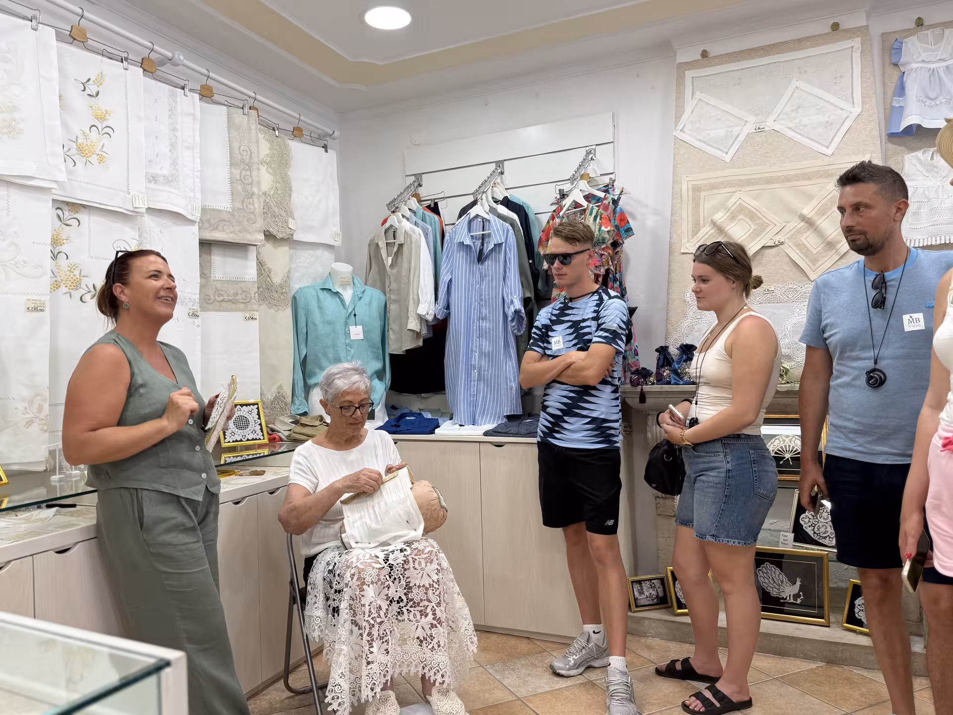 Tourists watch a local artisan demonstrate traditional lace-making in Burano, part of the Grand Tour experience.