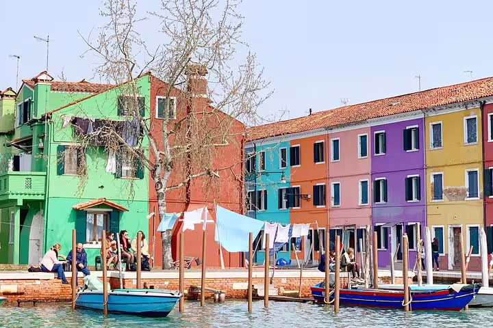 Bright Burano waterfront houses and boats on private Murano and Burano boat tour from Venice with lunch