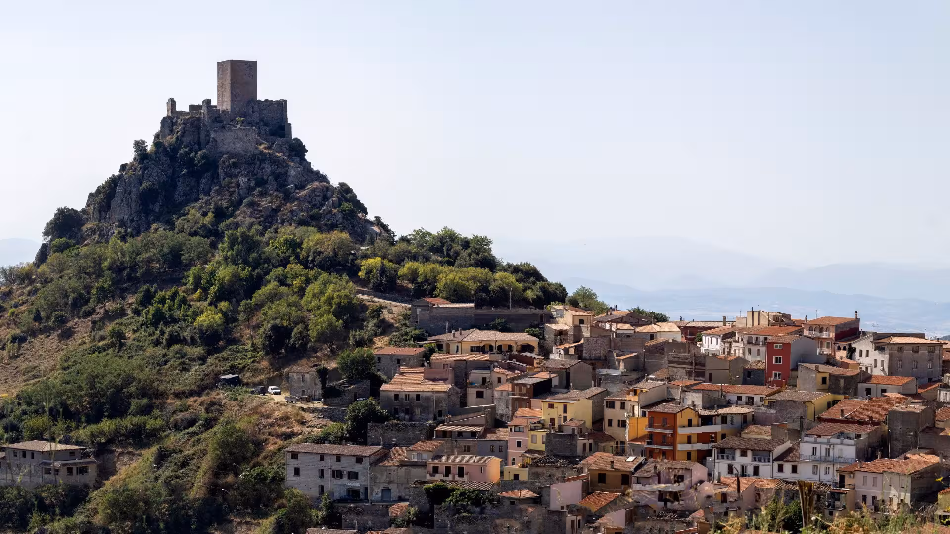 Scenic view of a historic Burgos village with a hilltop castle, perfect for cultural tours and sheep milking experiences.