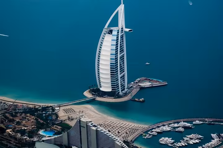 Aerial view of Burj Al Arab, Dubai Marina and sandy beaches, highlight of luxury private transfer route from Muscat to Dubai