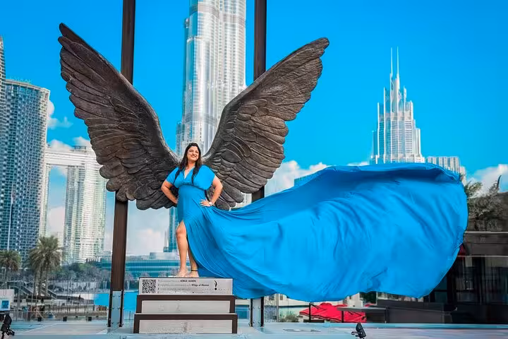 Woman in blue dress posing with wings in front of Burj Khalifa for a flying dress Instagram videography shoot.