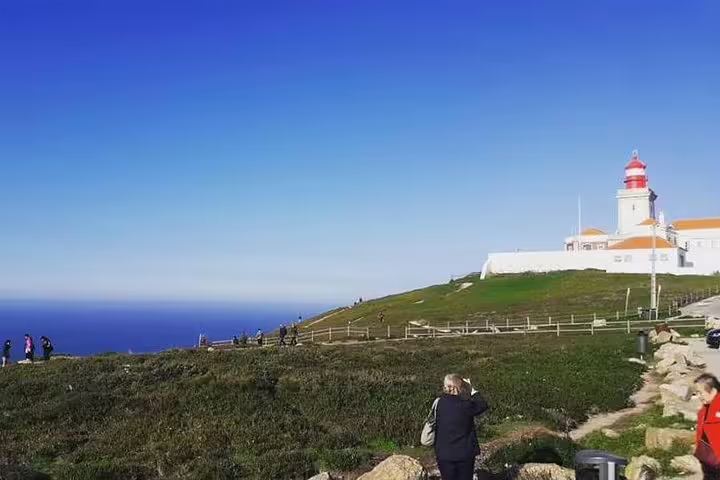 Tourists admire the scenic view of Cabo da Roca lighthouse and Atlantic Ocean during a private Sintra and Lisbon full-day tour.