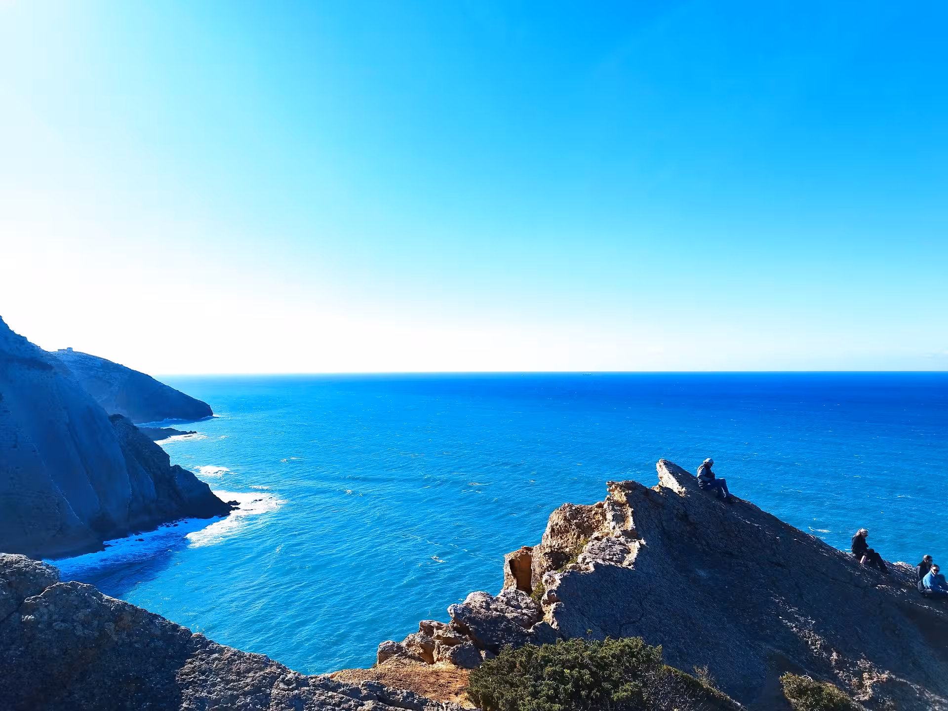 Hikers on rugged Cabo Espichel cliffs overlooking the Atlantic, en route to dinosaur footprints trail in Sesimbra