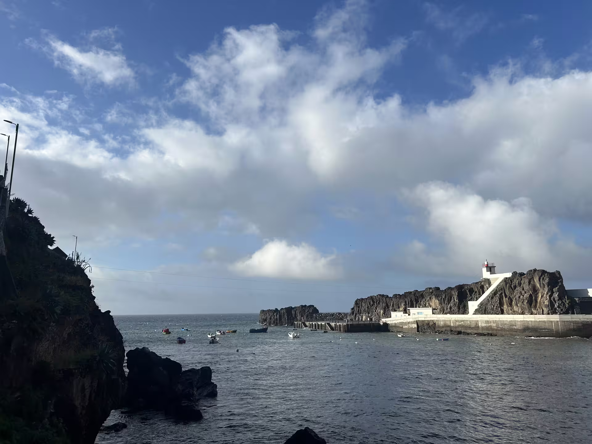 Scenic view of Cabo Girão cliffs and lighthouse with boats on the Atlantic Ocean, featured in the full-day West side tour.