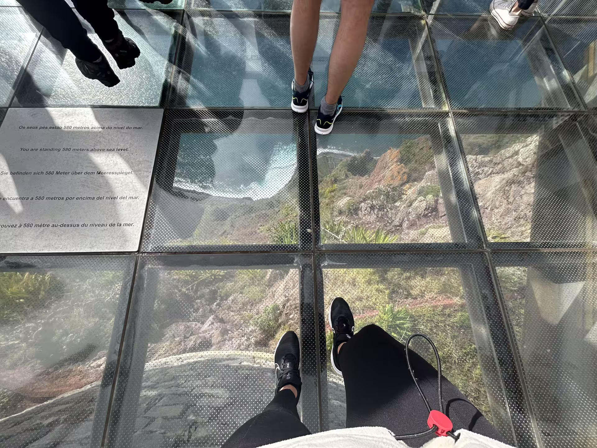 Visitors standing on Cabo Girão glass skywalk, 580 meters above sea level, offering breathtaking views, part of Madeira's full-day tour.