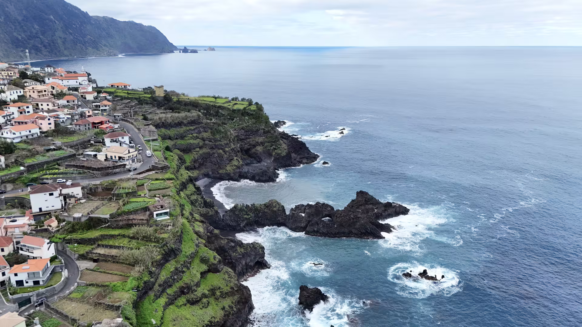 Aerial view of Madeira's stunning west coast with cliffs, terraced villages, and the Atlantic Ocean, part of the Cabo Girão tour.