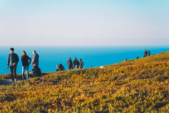 Visitors walking along Cabo da Roca's scenic cliffs with the Atlantic Ocean as a stunning backdrop.
