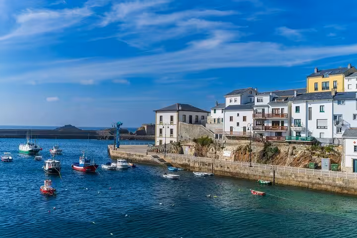 Picturesque coastal view of Cadiz harbor with colorful boats and waterfront buildings under a clear blue sky.