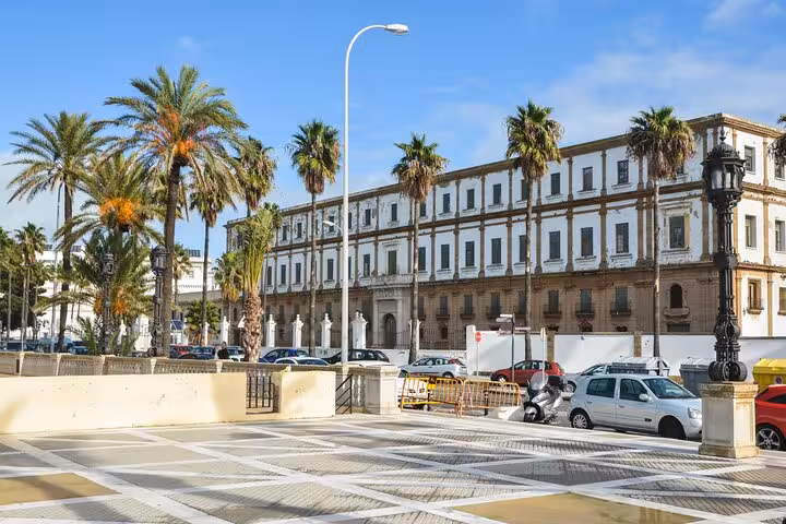Elegant historical building with palm trees lining the street, featured on the Hello Cadiz private guided city walk.