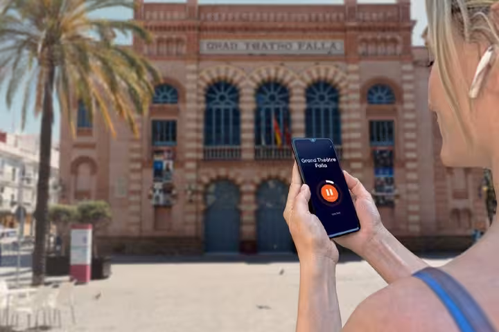 Tourist using audio guide app on smartphone in front of Grand Theatre Falla in Cadiz, Spain