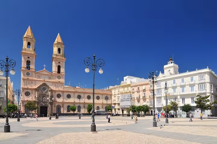 Plaza de San Antonio in Cadiz with baroque church towers and ornate street lamps under blue sky