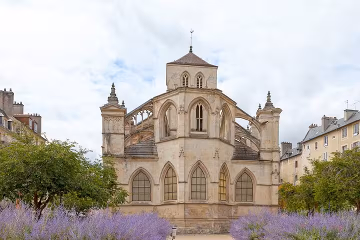Gothic apse of a medieval church with flying buttresses and lavender garden in Caen, France