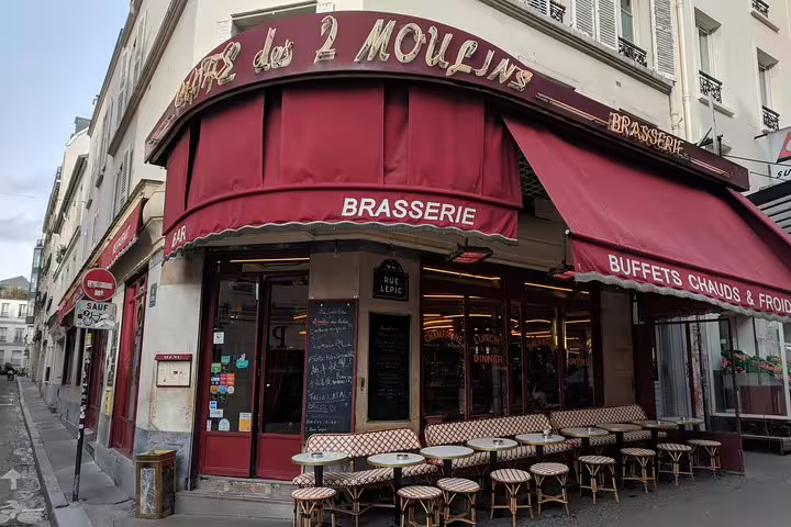 Café des 2 Moulins brasserie with red awnings and bistro chairs on Rue Lepic, Montmartre Paris