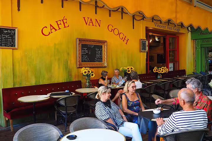 Café Van Gogh terrace with diners at outdoor tables, yellow walls, Arles France