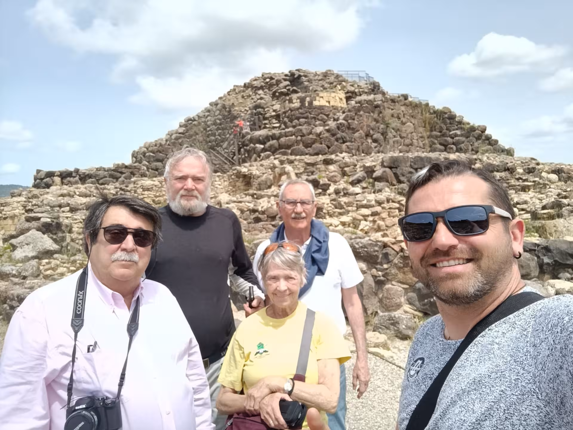 Group of visitors posing before the Nuraghe Su Nuraxi at Barumini, a UNESCO World Heritage site.