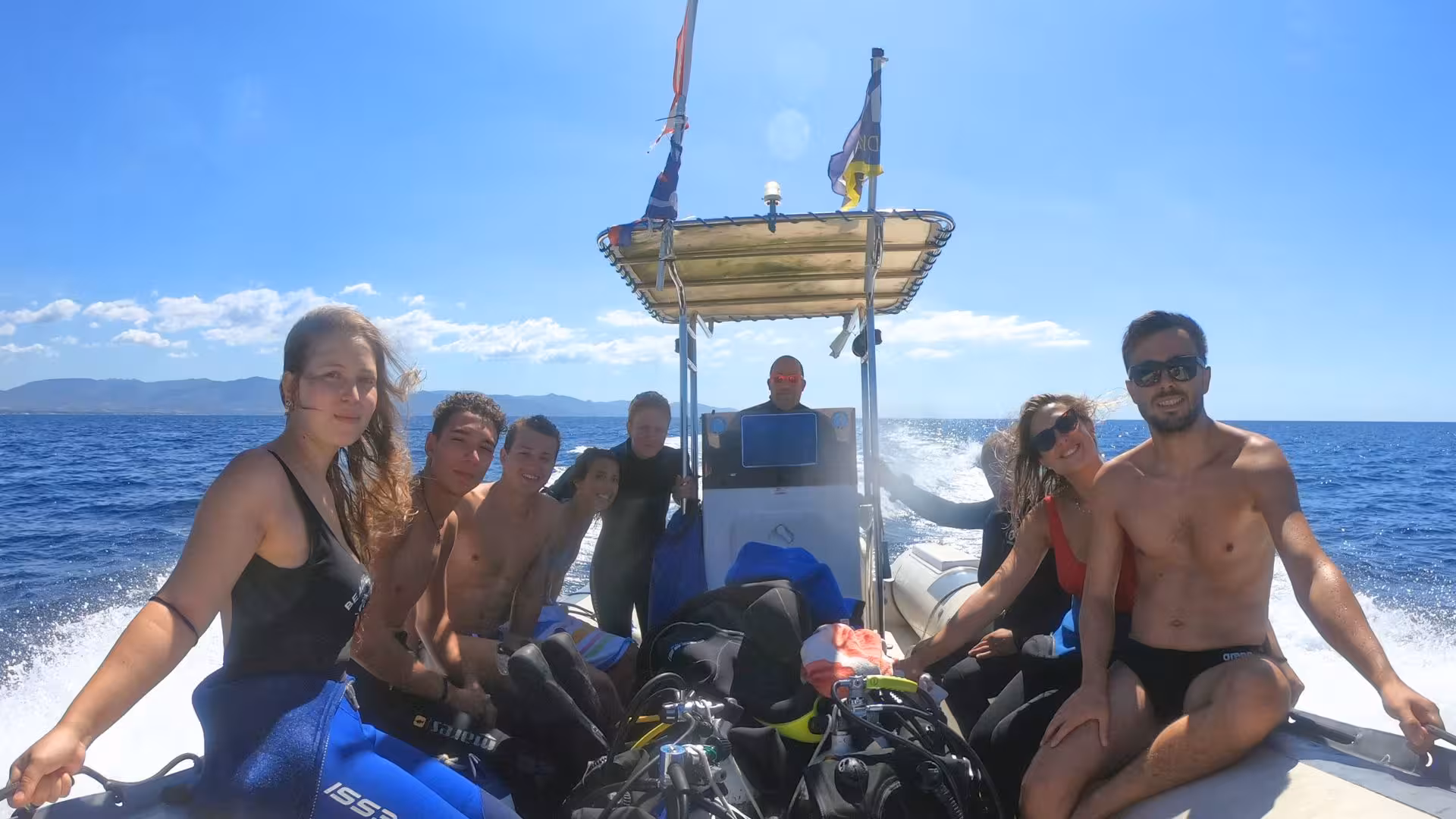 Group of excited beginners on a boat ready for scuba diving adventure in Cagliari's stunning coastline.