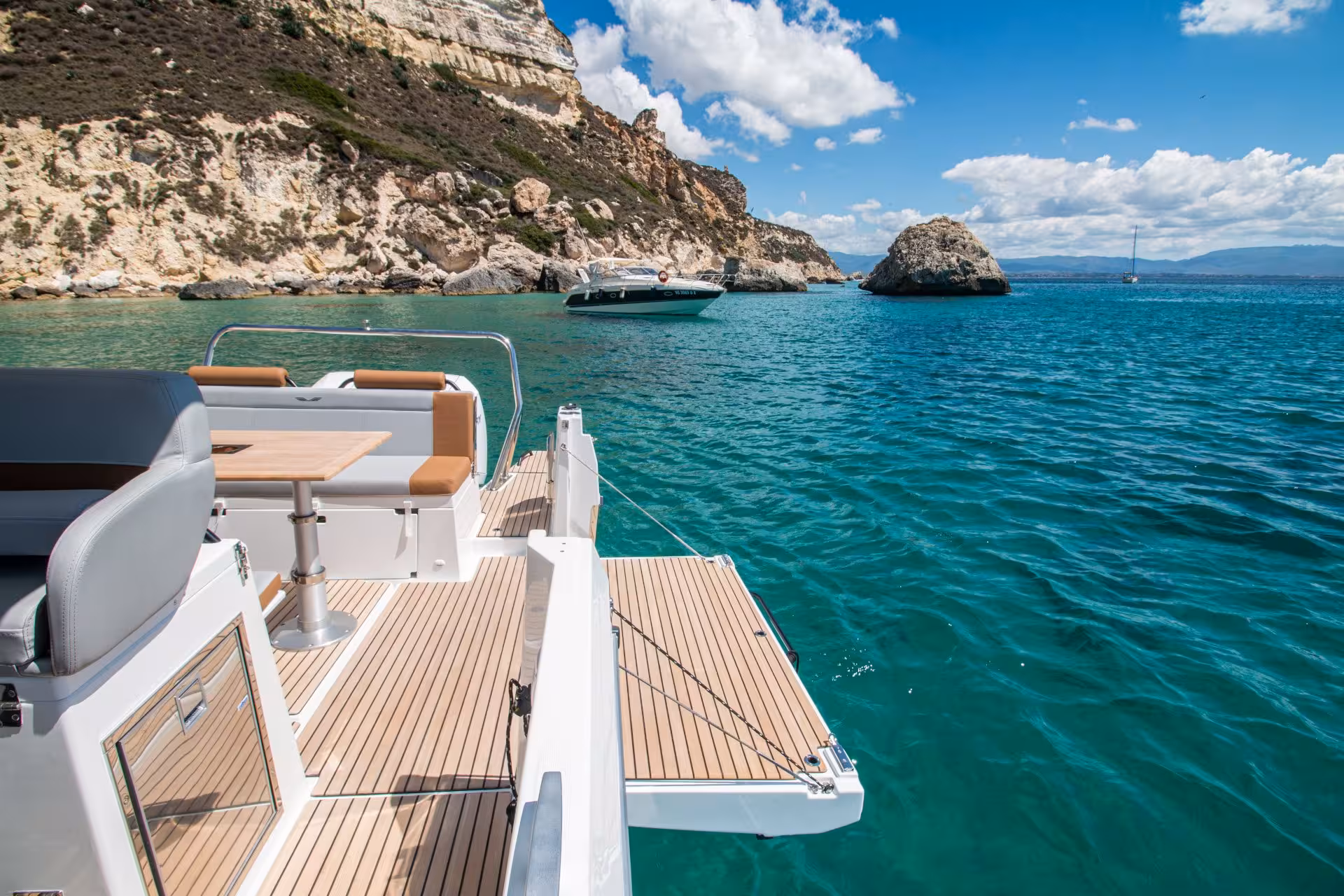 Luxurious boat deck overlooking Cagliari's clear turquoise waters and rocky coastline on a sunny day tour.