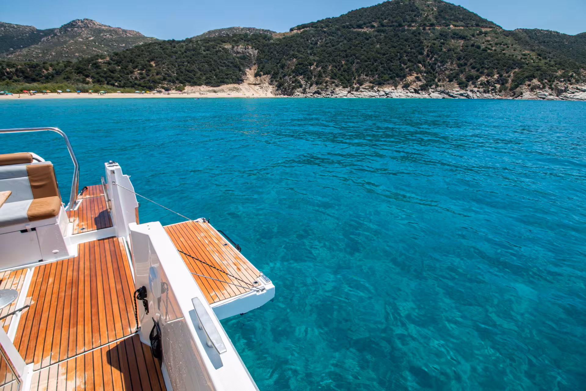 Scenic view of a boat deck overlooking turquoise waters and a lush shoreline during a Cagliari boat tour.