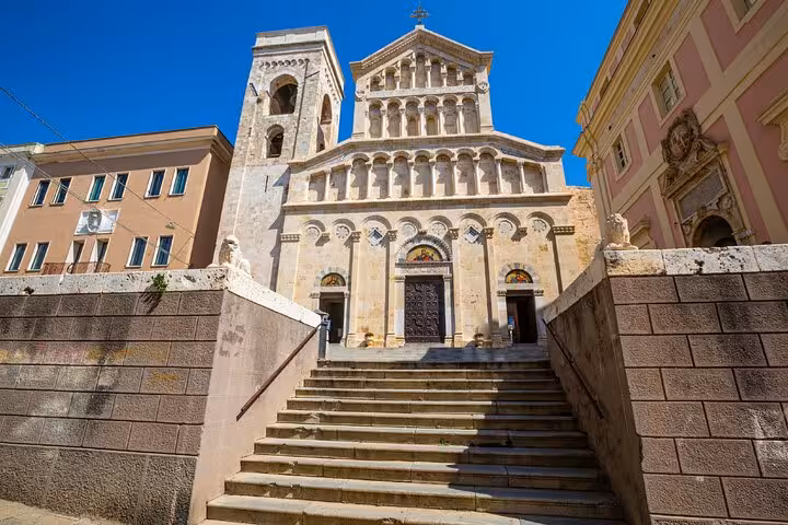 Stone staircase leading to Cagliari Cathedral facade with Romanesque architecture under blue sky