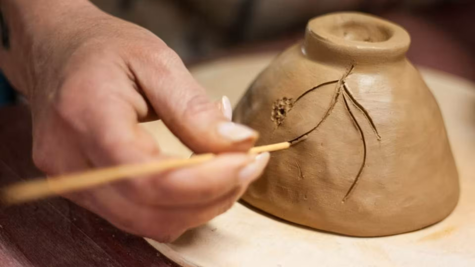 Detailing a clay pot with precision tools at a Cagliari ceramics workshop session.