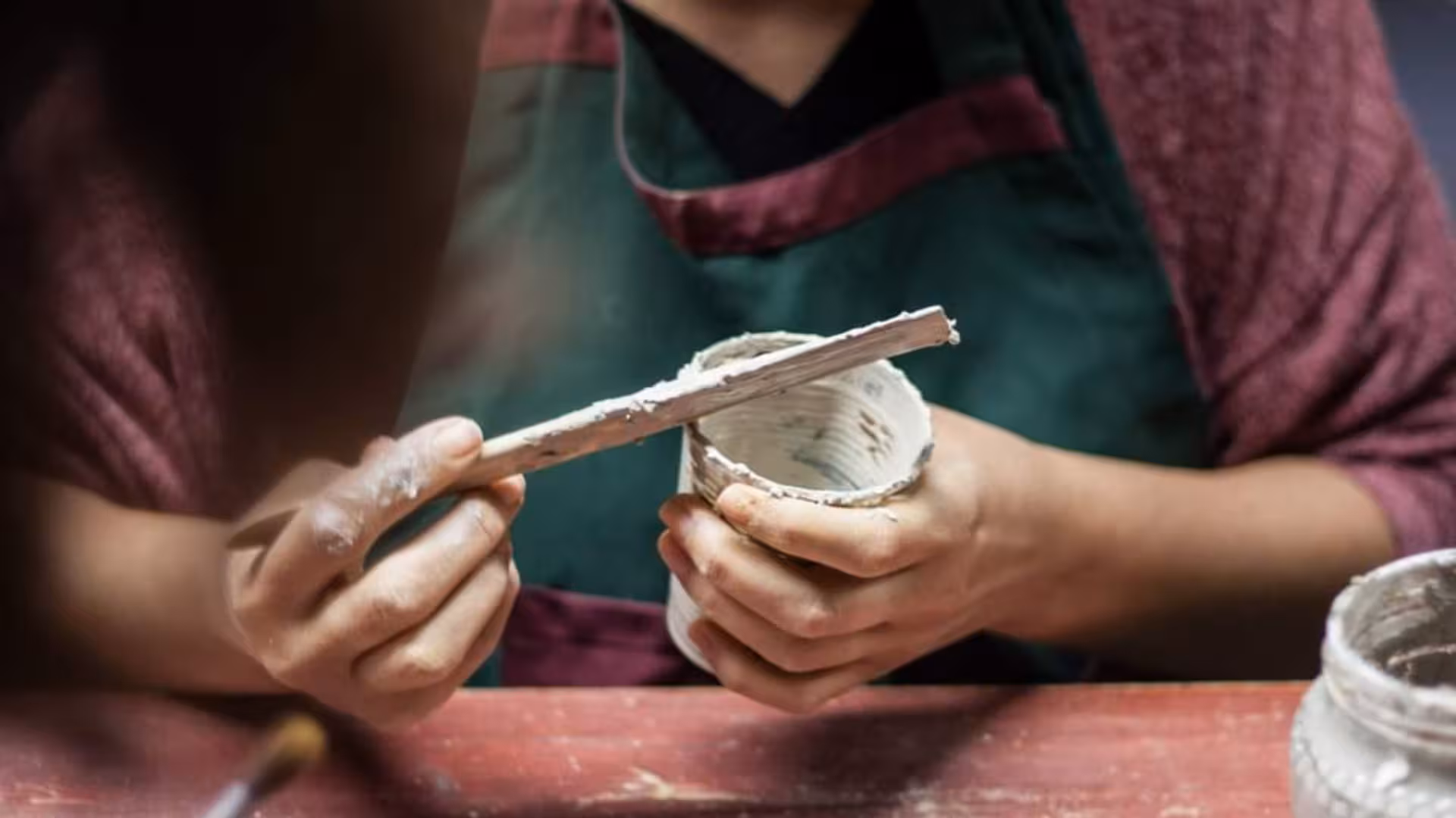 Detail of a participant applying glaze to a clay pot at a Cagliari ceramics workshop, showcasing artistic techniques.