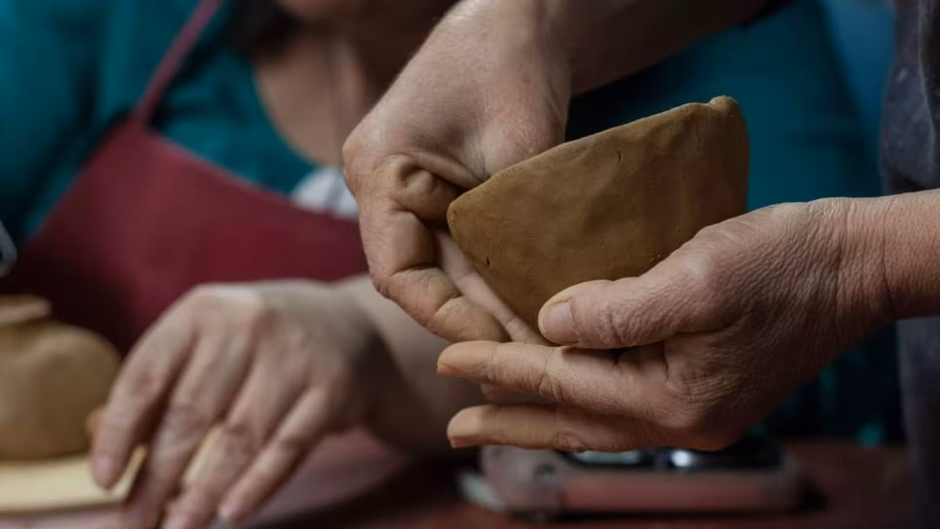 Close-up of hands molding clay at a Cagliari ceramics workshop, perfect for creative pottery enthusiasts.