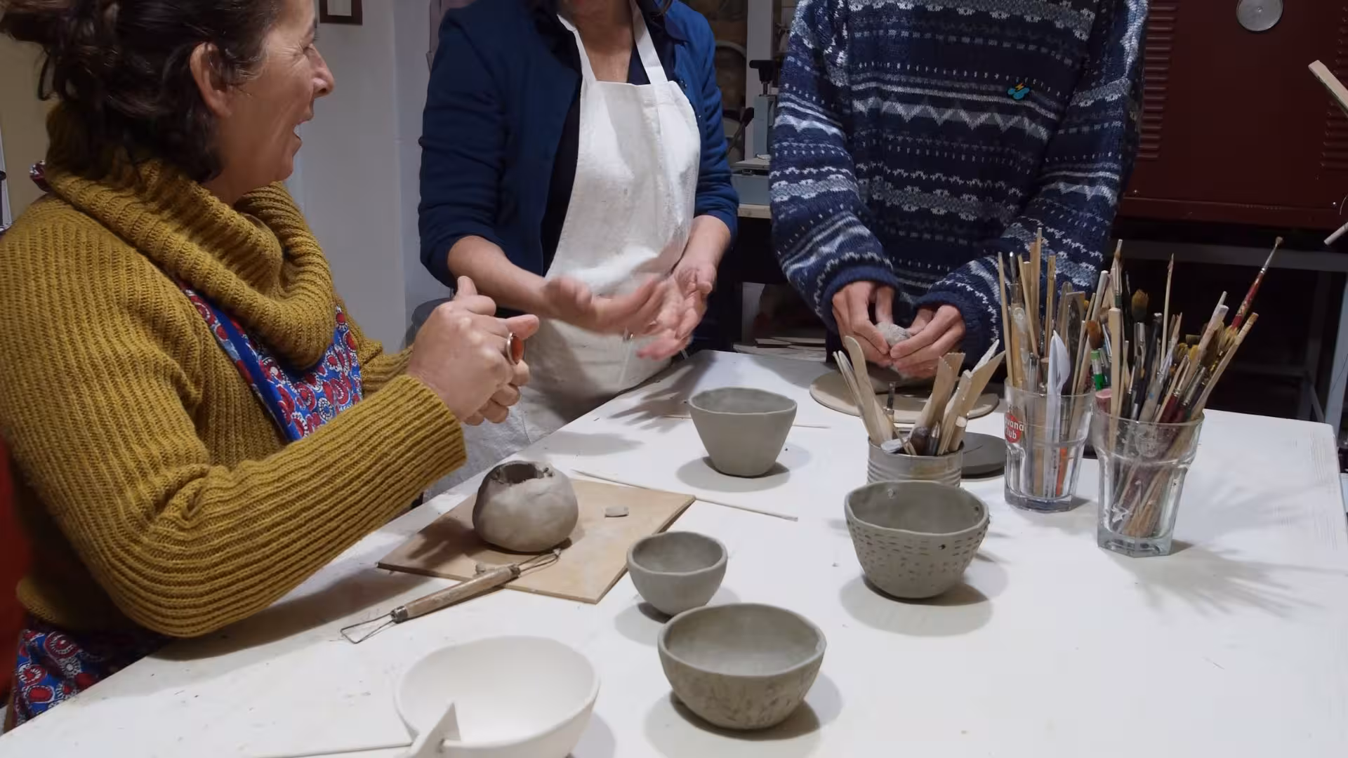 Participants engage in hands-on pottery making at a Cagliari ceramics workshop, surrounded by tools and clay creations.