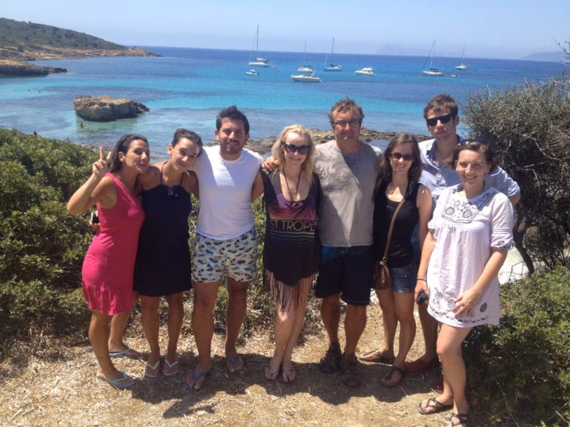 Group of friends posing by the scenic coastline with turquoise waters on a jeep tour from Cagliari to Chia.