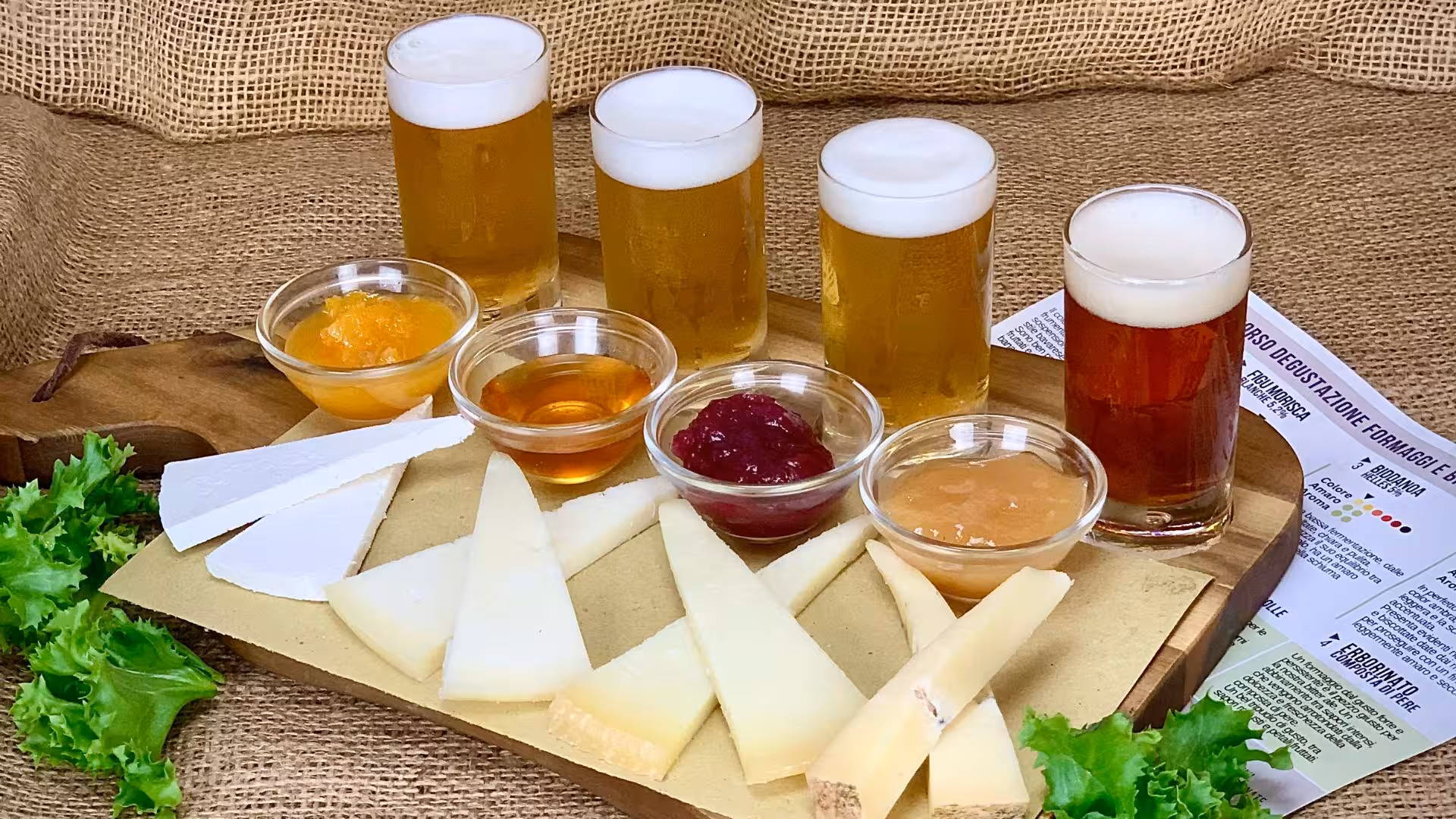 Cagliari craft beer tasting with five beer samples, assorted cheeses, and fruit jams on a wooden board.