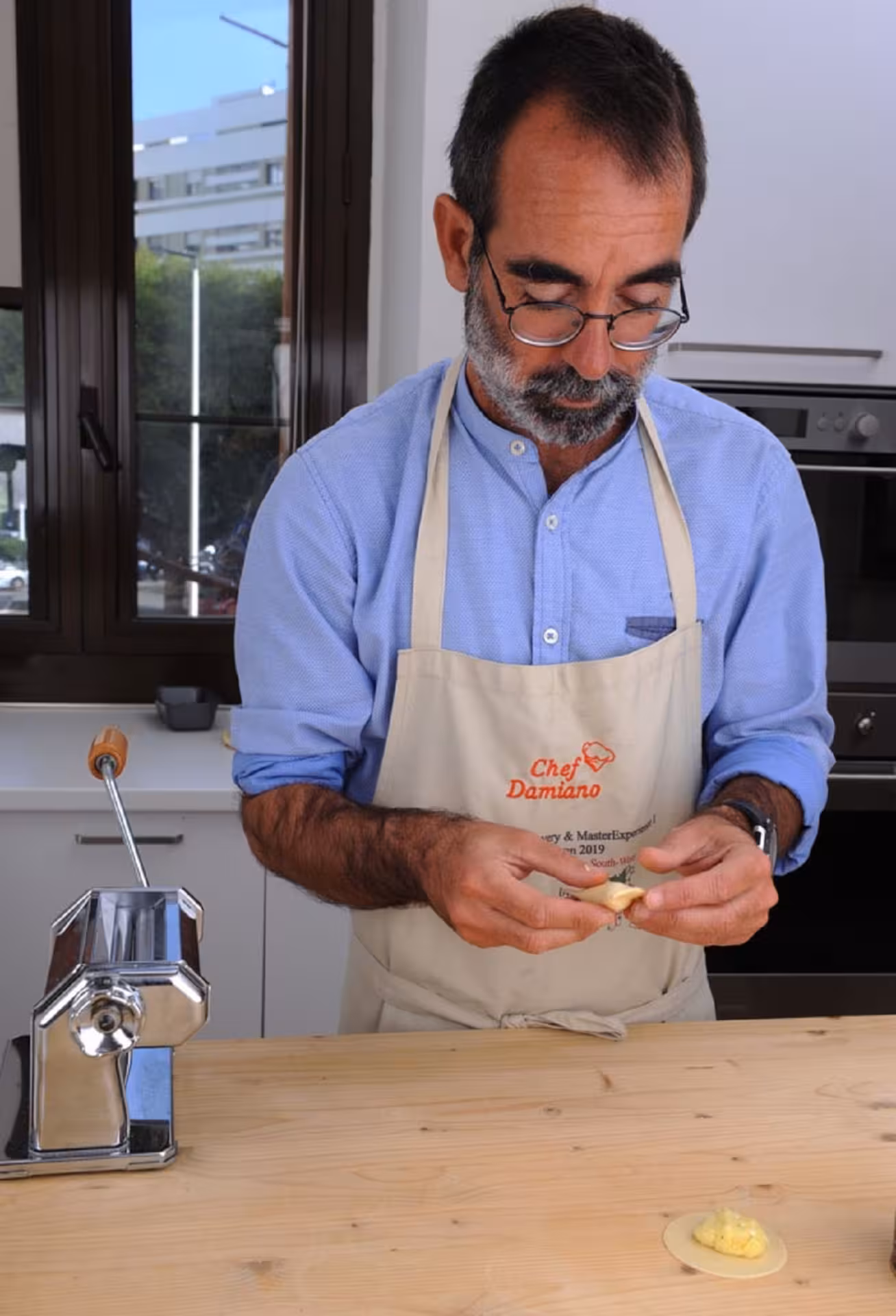 Chef in Cagliari preparing traditional culurgiones during a hands-on cooking class with pasta machine.