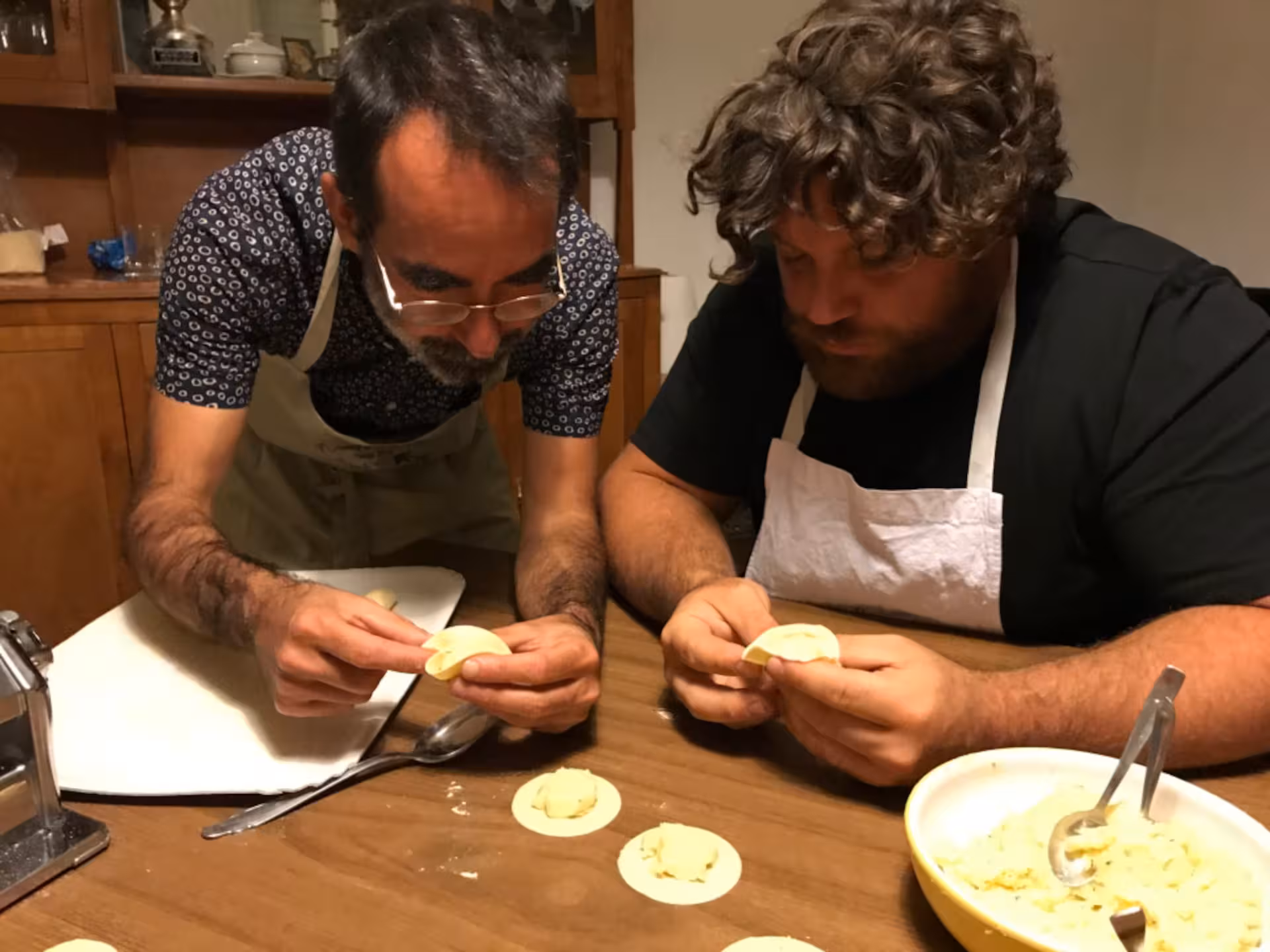 Two individuals focus on crafting perfect culurgiones in a traditional Cagliari cooking class.