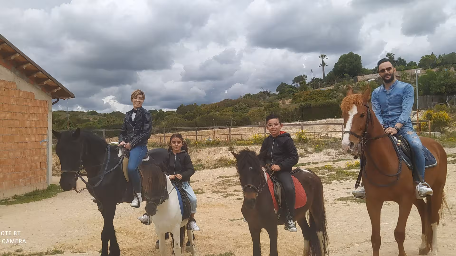 Family enjoying panoramic horseback riding in Cagliari with scenic views and lush greenery.