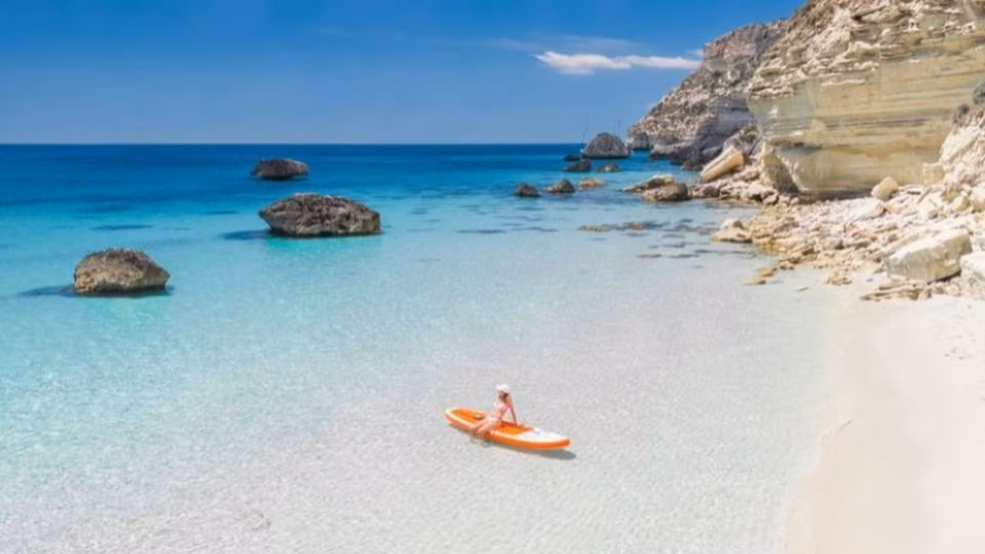 Serene beach with crystal-clear waters and rocky cliffs in the Gulf of Angels, perfect for relaxation.