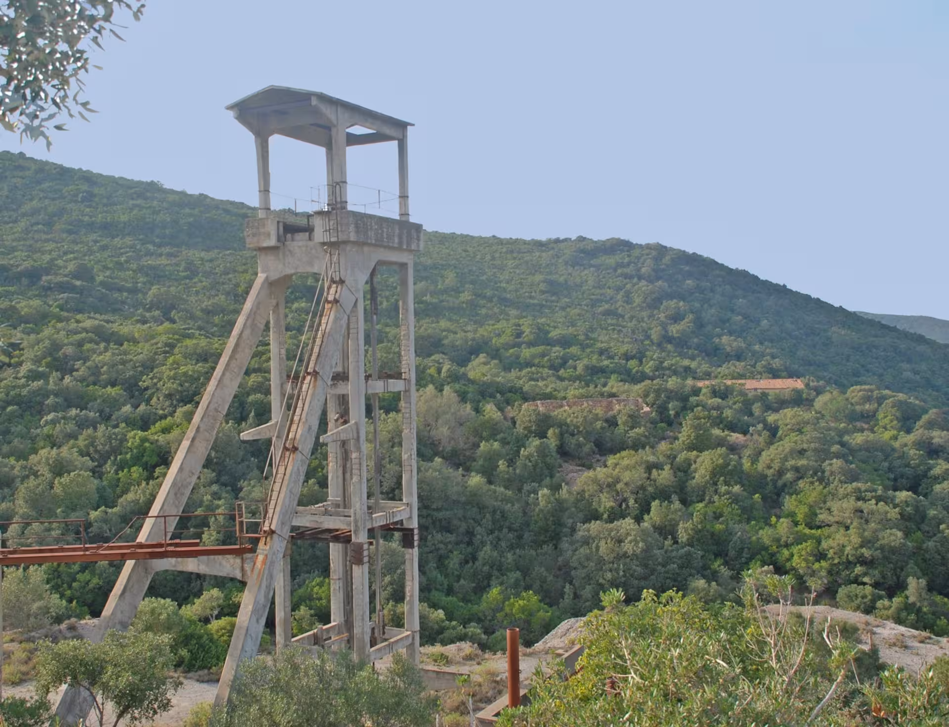 Historic mining structure stands amid lush greenery on a guided tour through the Sardinian countryside near Cagliari.