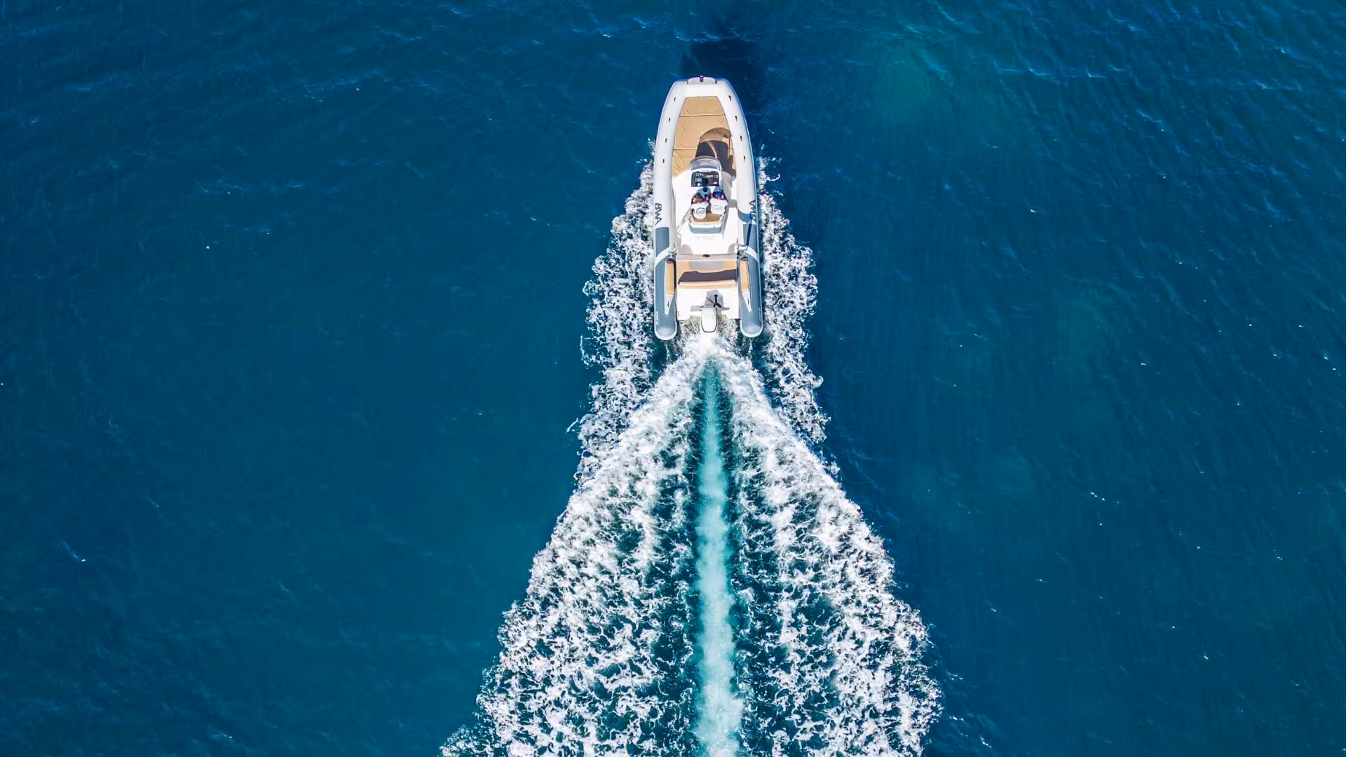 Aerial view of a RIB boat cruising through the deep blue waters of Cagliari, Sardinia on a sunny day.