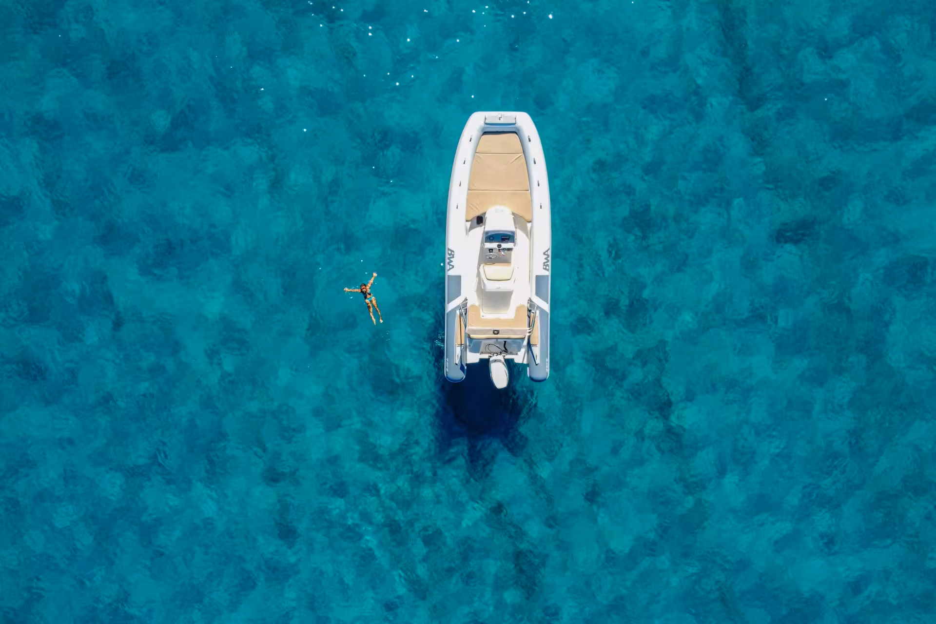 Aerial shot of a RIB boat in Cagliari, with a swimmer in the crystal-clear Mediterranean sea.