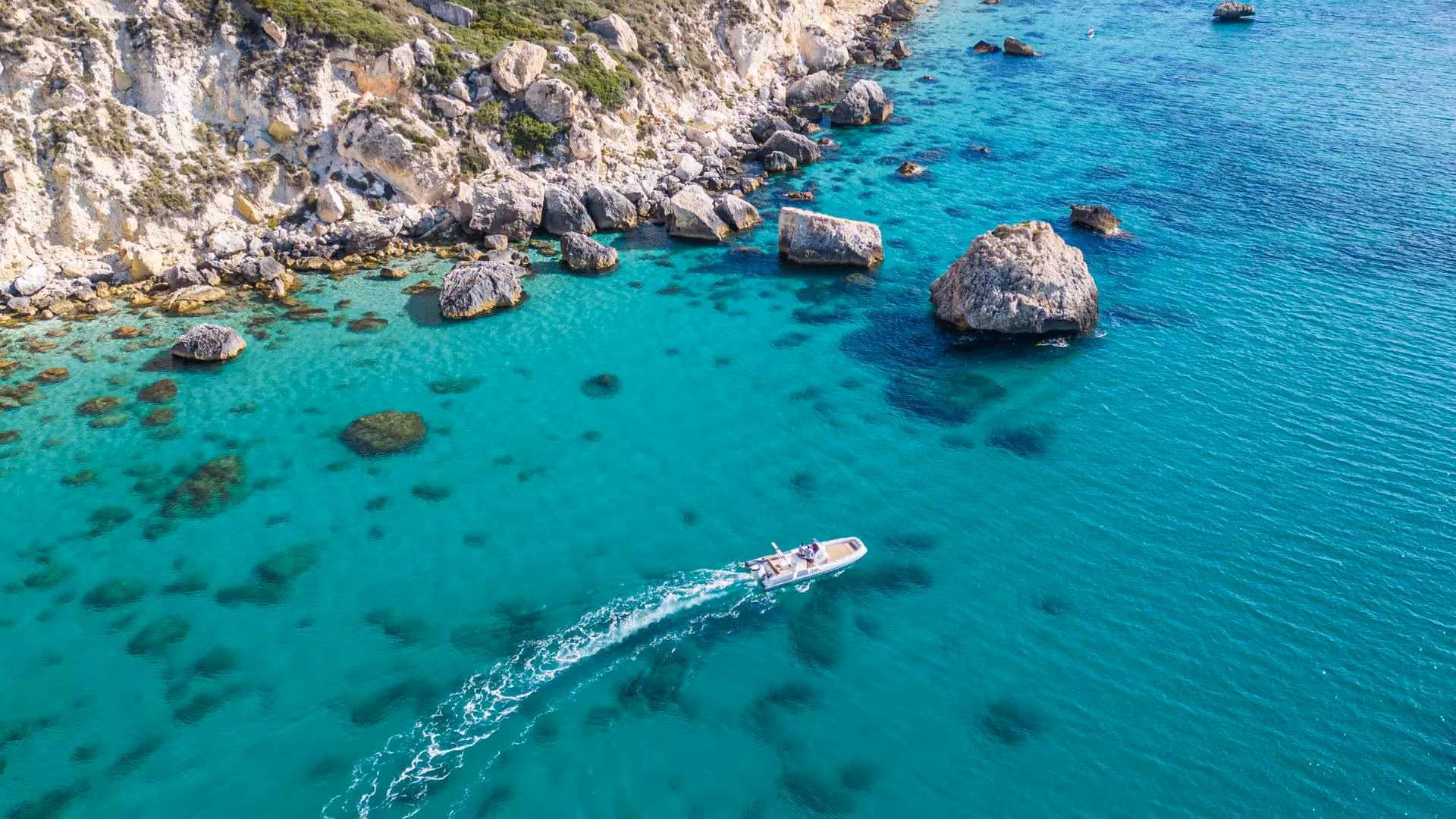 RIB boat navigating the turquoise waters near rocky cliffs in Cagliari, perfect for an adventurous Sardinian tour.